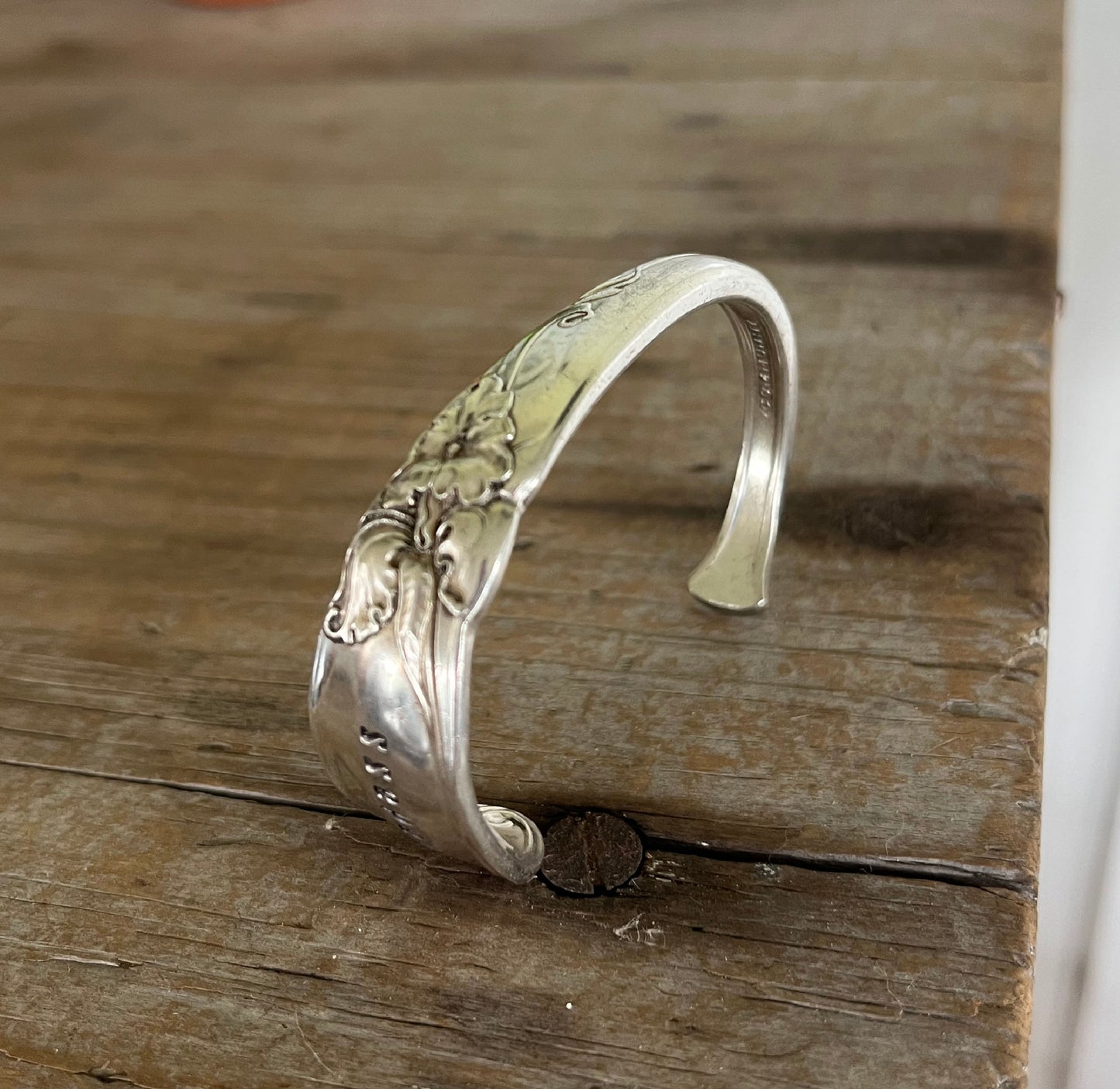 Detail of White Orchid pattern on hand-stamped spoon cuff bracelet from Community Silverplate with BADASS message and floral design