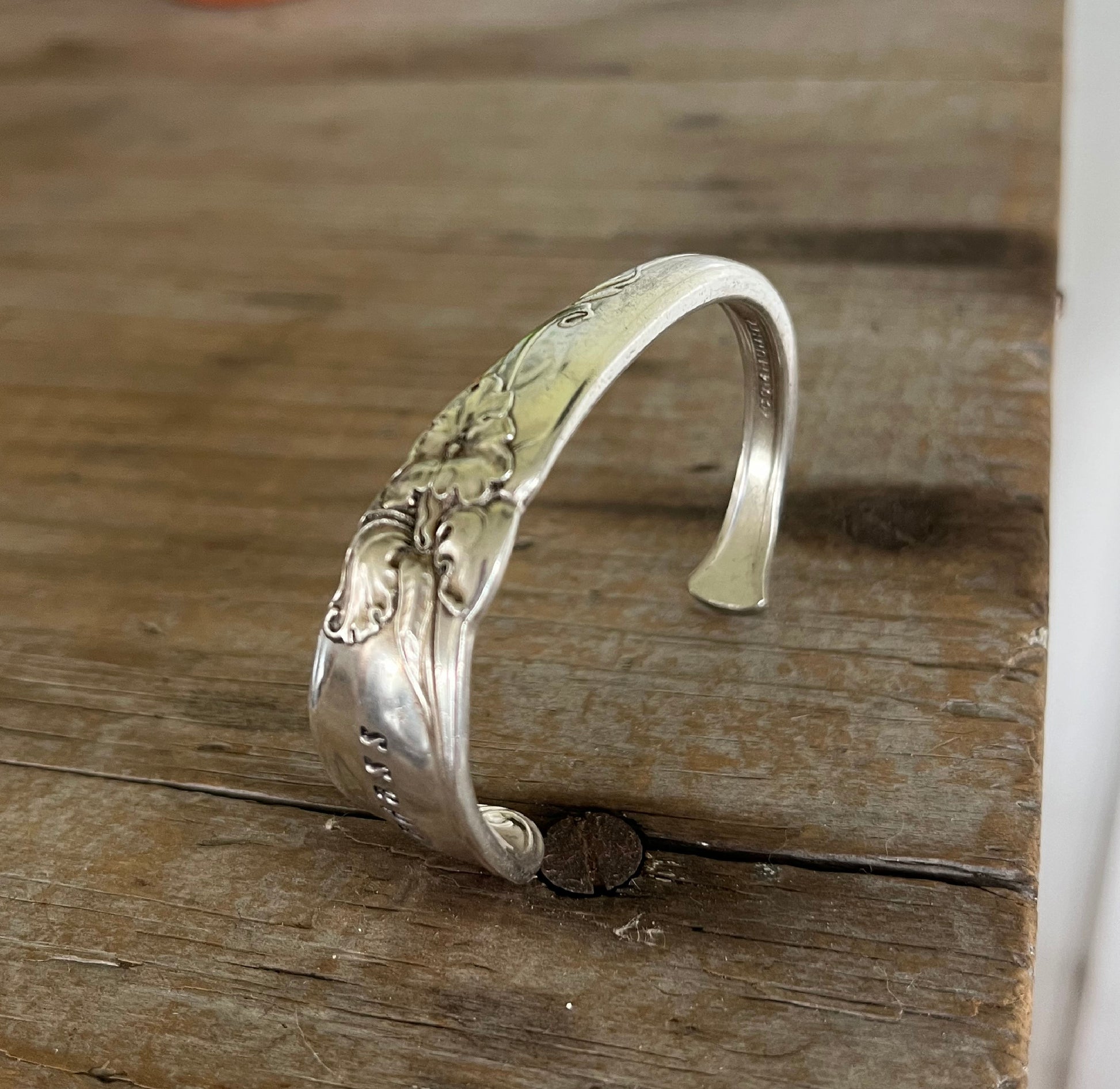Detail of White Orchid pattern on hand-stamped spoon cuff bracelet from Community Silverplate with BADASS message and floral design