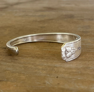 inside view of silver spoon cuff bracelet from Prestige Silverplate Bordeaud pattern stamped fuckity fuck fuck on wood surface - handcrafted from upcycled vintage silverware - Laughing Frog Studio