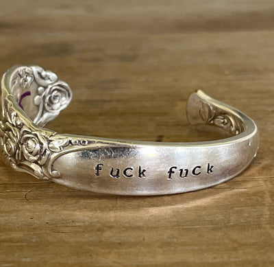 Top view of silver spoon cuff bracelet with floral rose pattern stamped fuckity on wood surface - Oneida Ballad cuff bracelet - handcrafted from upcycled vintage silverware - Laughing Frog Studio