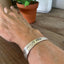 FUCKITY FUCK FUCK hand-stamped message on vintage Tudor Plate silverplate spoon cuff bracelet worn on model wrist - hand-stamped spoon cuff bracelet - handcrafted from upcycled vintage silverware - Laughing Frog Studio