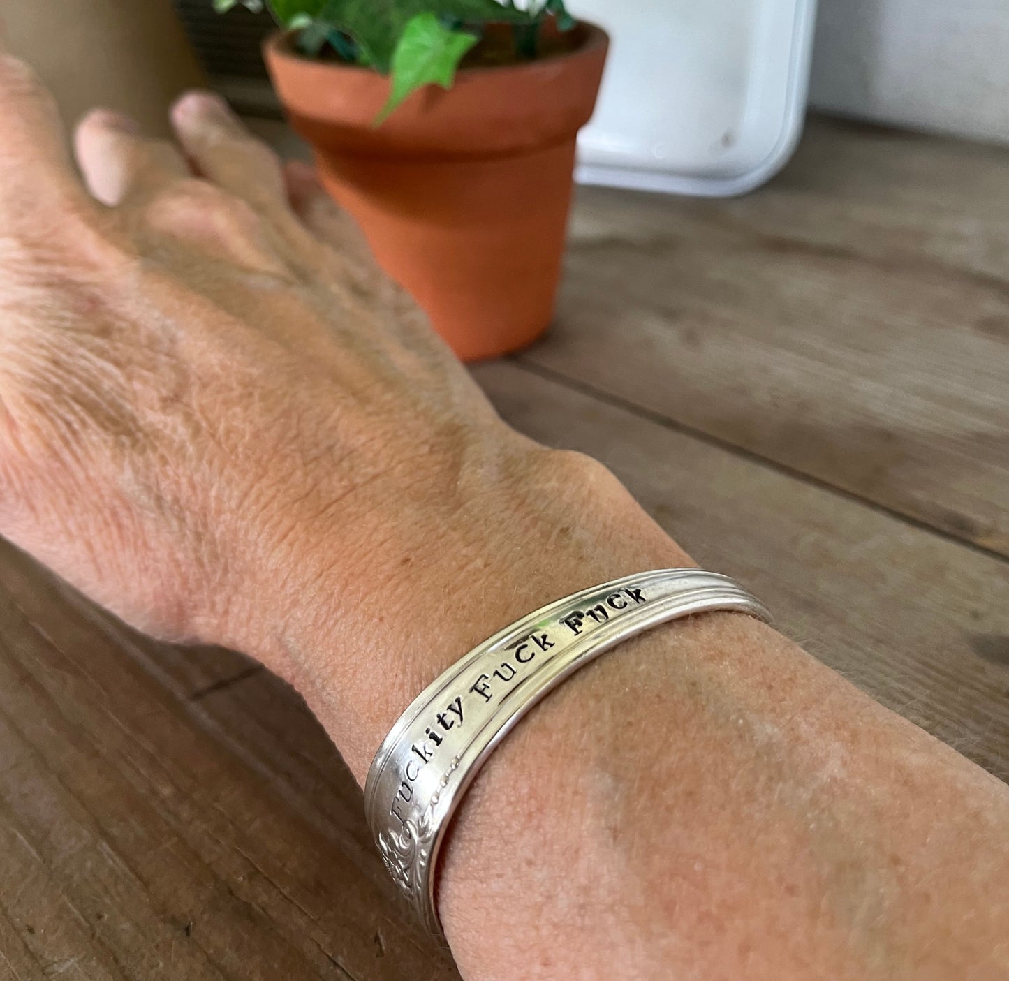 FUCKITY FUCK FUCK hand-stamped message on vintage Tudor Plate silverplate spoon cuff bracelet worn on model wrist - hand-stamped spoon cuff bracelet - handcrafted from upcycled vintage silverware - Laughing Frog Studio