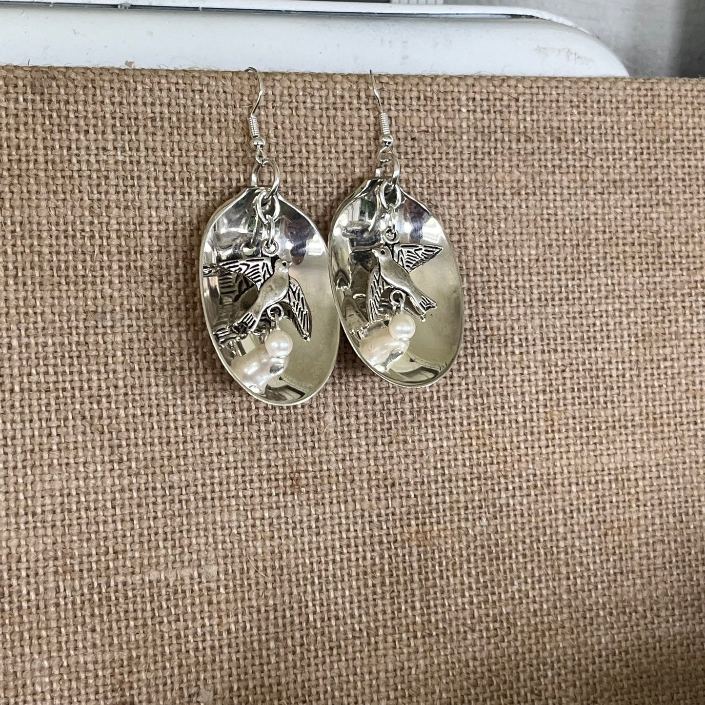 Handcrafted baby spoon bowl earrings with peace bird charms showing unique upcycled silverware design