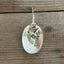 Detail view of vintage silverplate baby spoon earrings with dangling bird charm and faux pearl bead