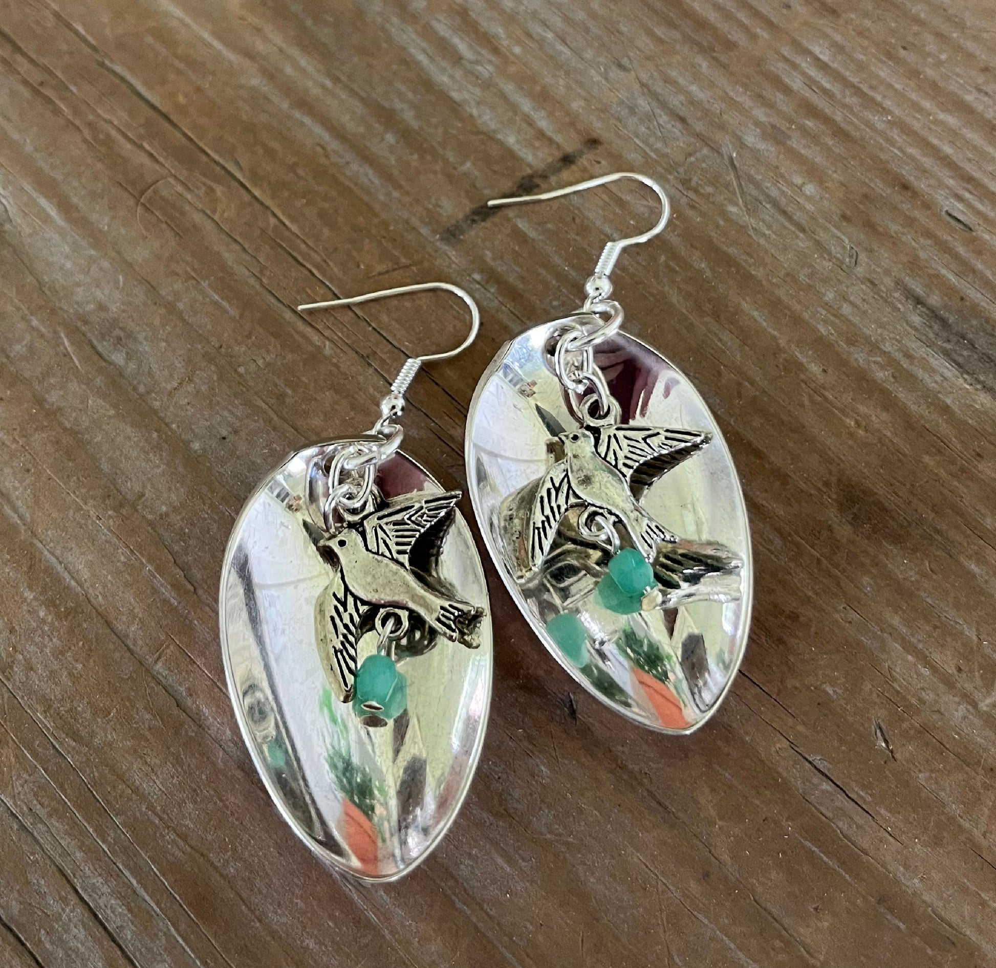 Close-up detail of demitasse spoon bowl earrings with hanging bird charm and faceted dark jadeite bead, 2.375 inches long - Spoon Earrings - handcrafted from upcycled vintage silverware - Laughing Frog Studio
