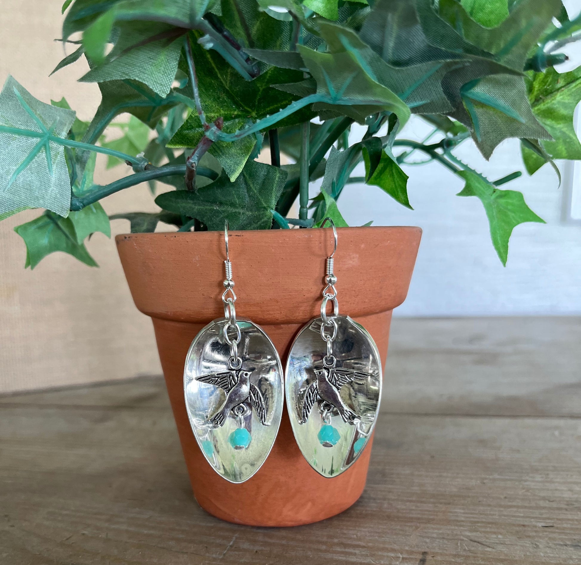Demitasse spoon earrings with bird of peace charms and jadeite glass beads displayed on flower pot - Spoon Earrings - handcrafted from upcycled vintage silverware - Laughing Frog Studio