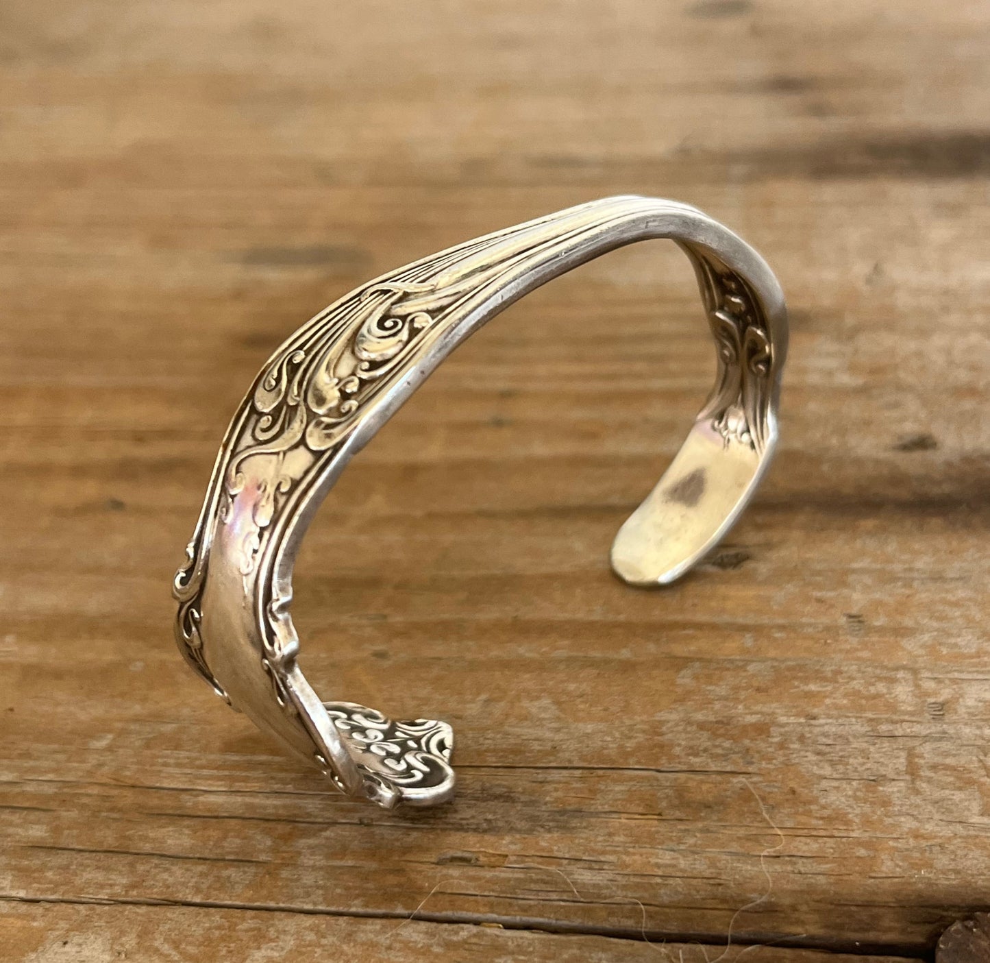 Close-up detail of Tudor pattern spoon cuff bracelet showing Art Nouveau botanical flourishes and vintage silverplate