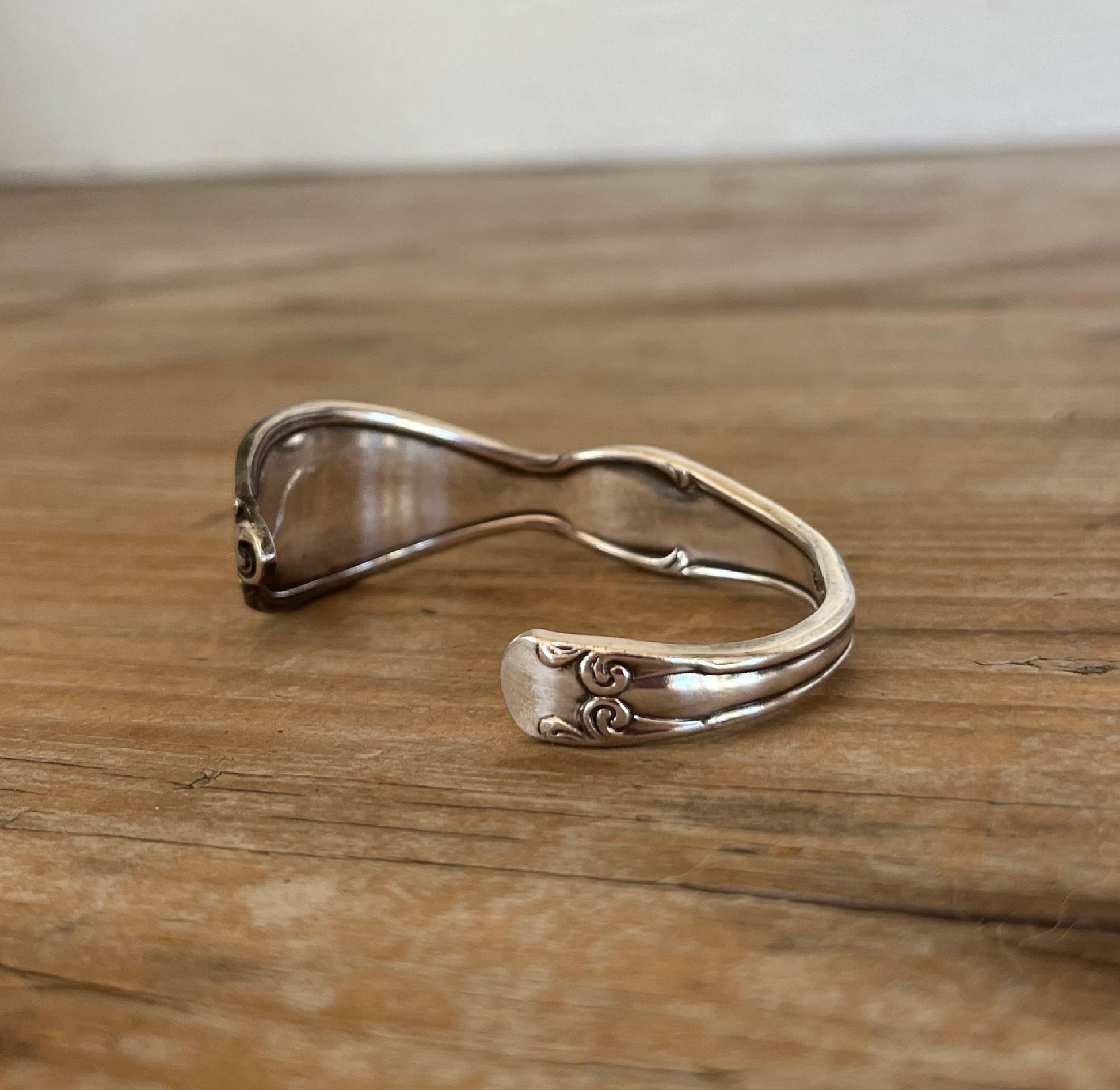 Detailed lfat lay view of Top view of 1949 Old Soutth spoon cuff bracelet with decorative border - upcycled vintage silverware - Laughing Frog Studio