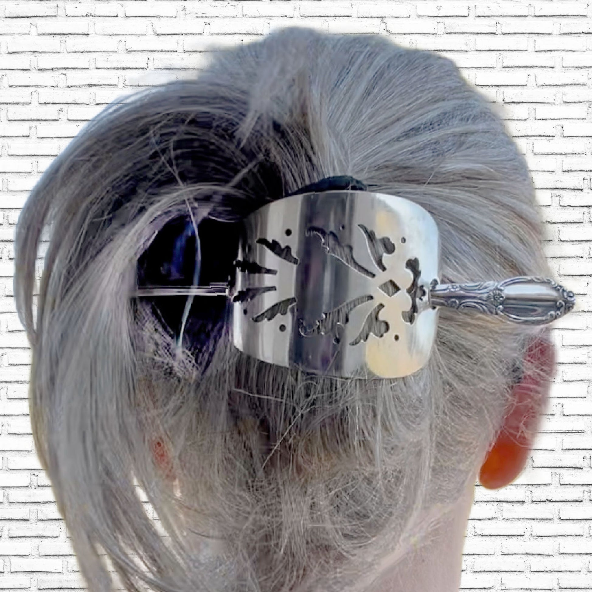 Handcrafted cake server hair barrette accessorizing bun hairstyle displaying punched silverware texture in hair