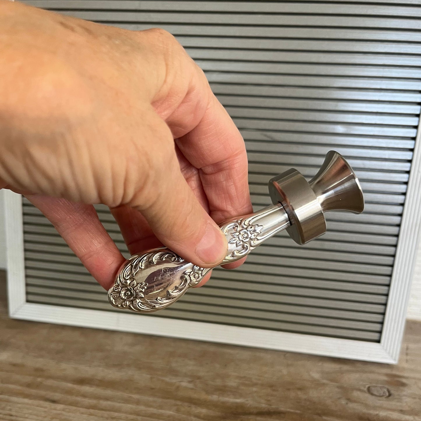 Hand holding William Rogers Grand Elegance pattern knife bottle opener with ornate floral handle - handcrafted upcycled vintage silverware accessory - Laughing Frog Studio