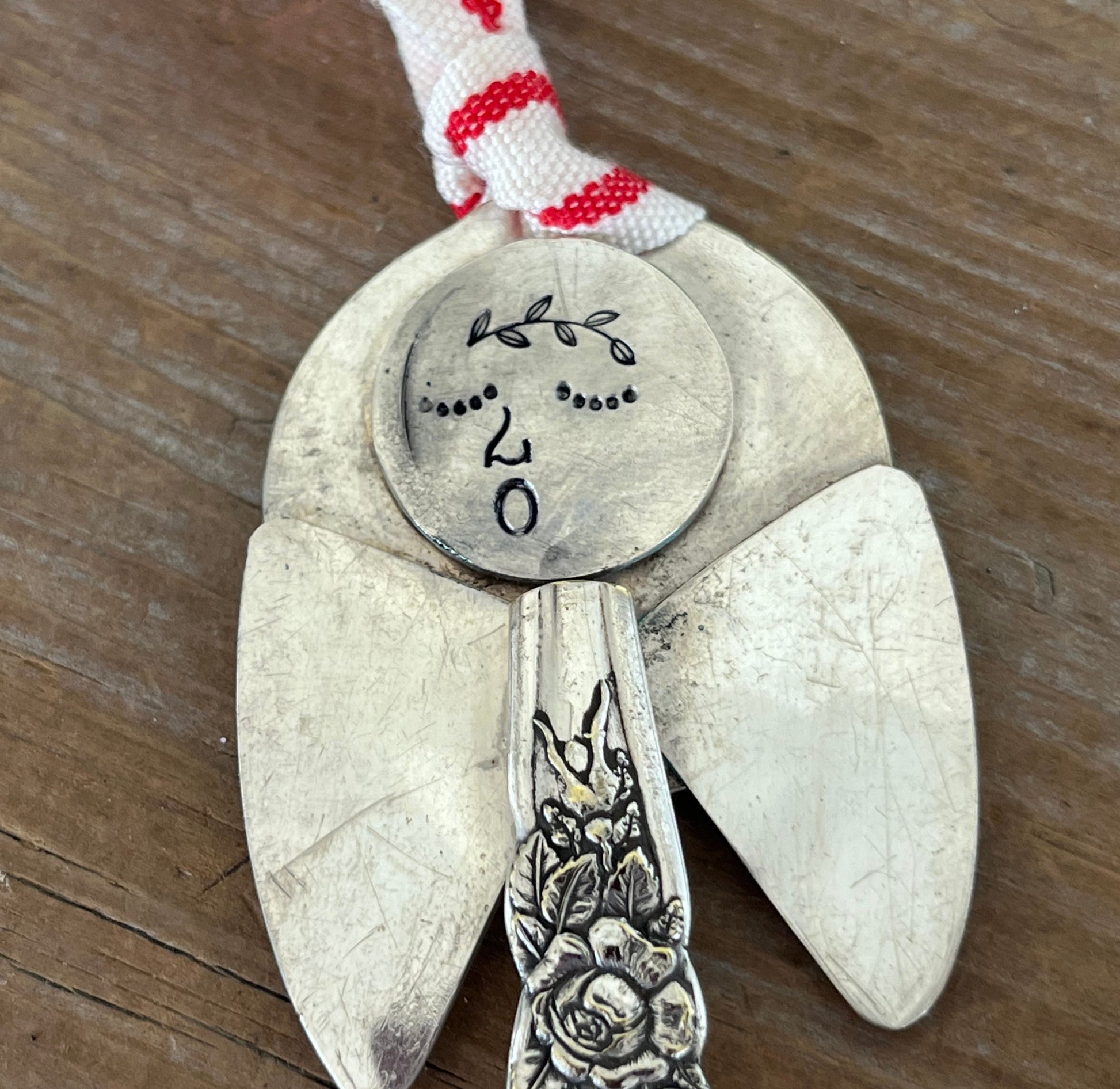 Cloe up of hand-stamped face of Minerva artisan angel ornament with spoon handle body and spoon bowl wings - handcrafted upcycled vintage silverware ornament - Laughing Frog Studio