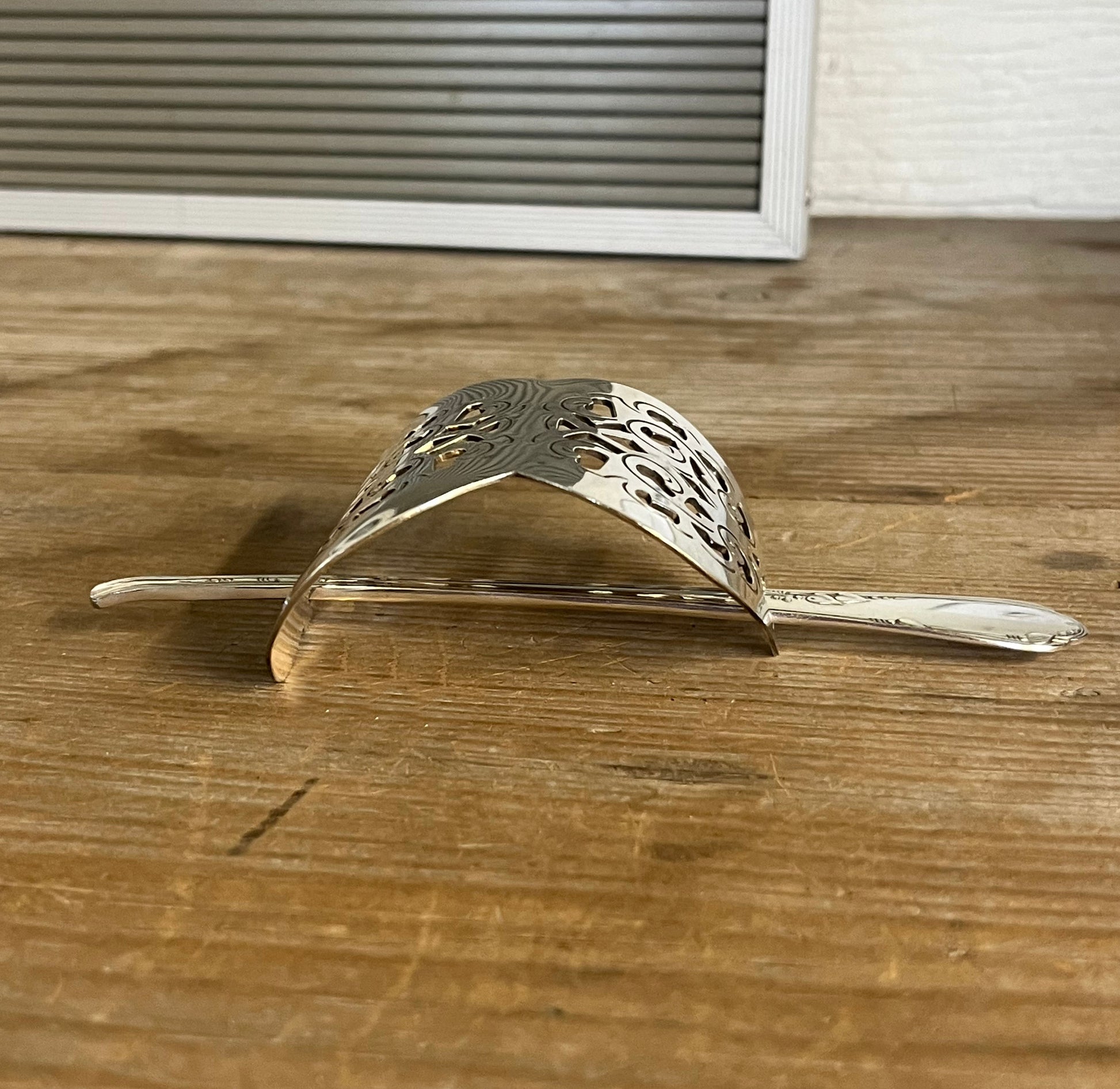 Arc view of Danish cake server hair barrette with filigree floral cutout and meadow flower stick pin - handcrafted upcycled vintage silverware hair accessory - Laughing Frog Studio