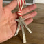 Scrap silverware Christmas tree shaped ornament with a star and red striped ribbon hanger shown in hand for scale - handcrafted upcycled vintage silverware ornament - Laughing Frog Studio
