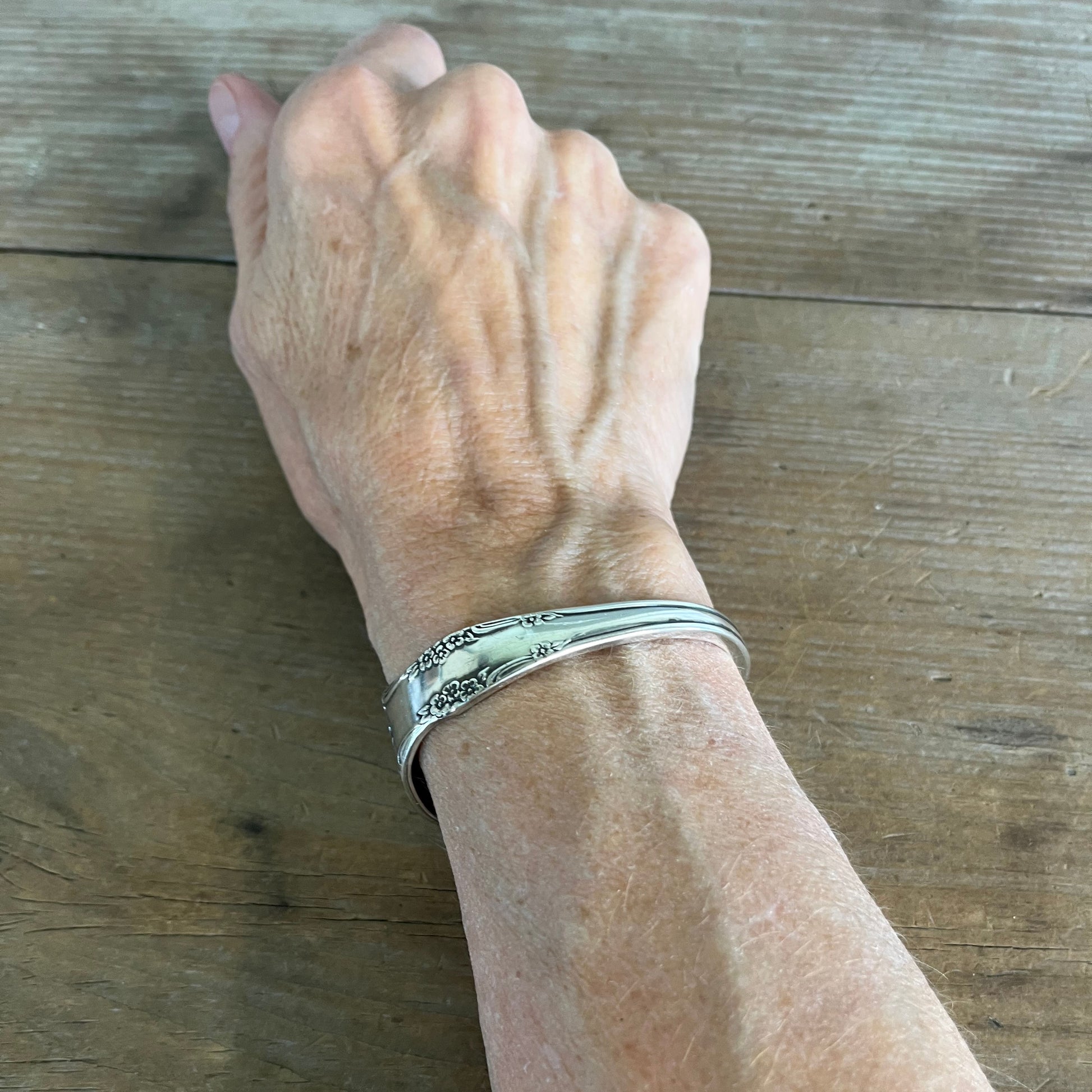 Affection pattern silverplate cuff bracelet worn on wrist top view - upcycled vintage silverware jewelry - Laughing Frog Studio