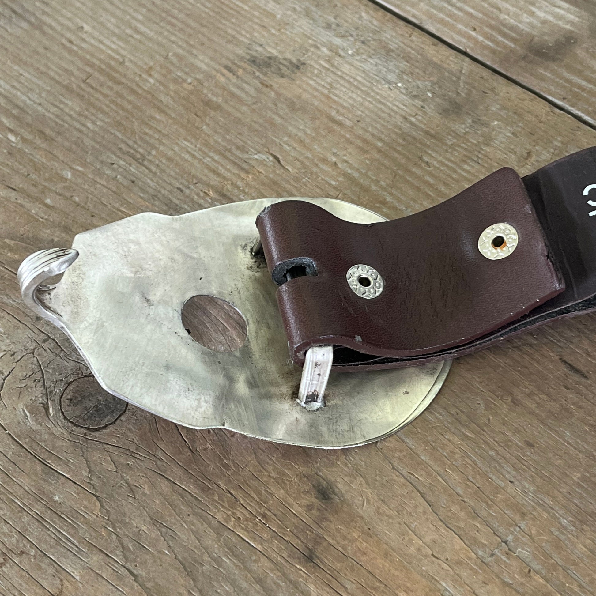 Guitar-shaped belt buckle handcrafted from upcycled vintage silverplate casserole spoon shown on a snap belt mechanism - one-of-a-kind wearable art for music lovers - Laughing Frog Studio