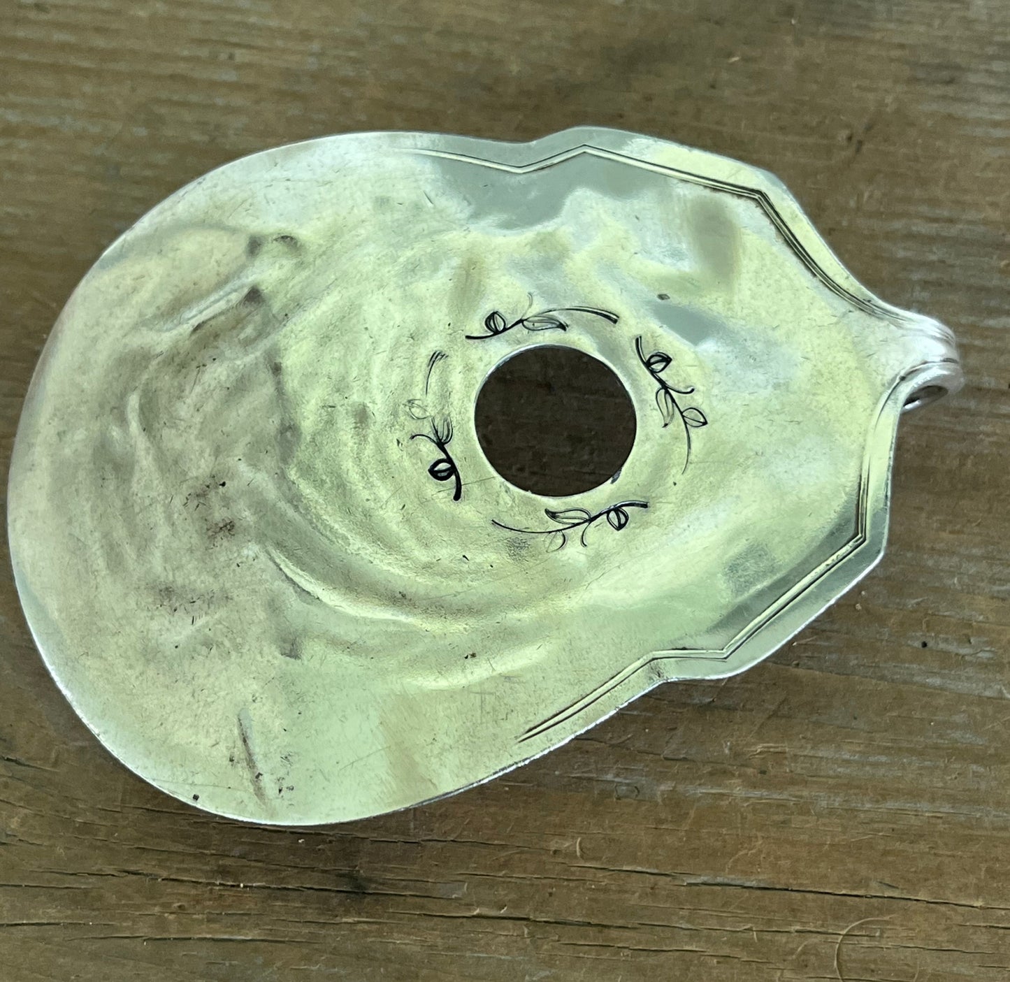 Close-up of hand-stamped vine scrollwork around guitar sound hole - upcycled vintage silverware belt buckle - Laughing Frog Studio