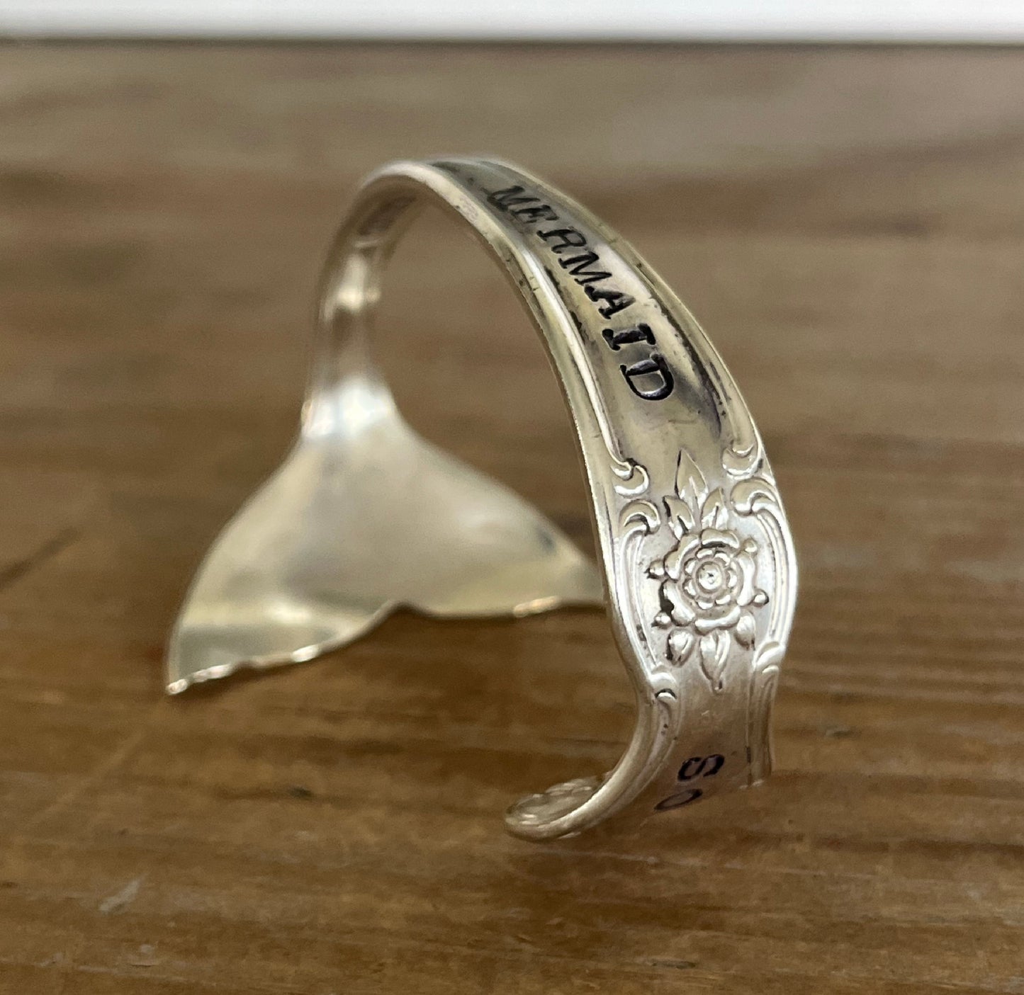 Side view of Mermaid Soul spoon cuff bracelet showing hand-stamped band and Signature pattern rose engraving with carved mermaid tail fin - handcrafted from upcycled vintage silverware - Laughing Frog Studio