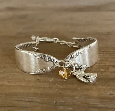 Front view of King Edward spoon link bracelet with silver bird charm, golden crystal, and clear bead - handcrafted from upcycled vintage silverware - Laughing Frog Studio