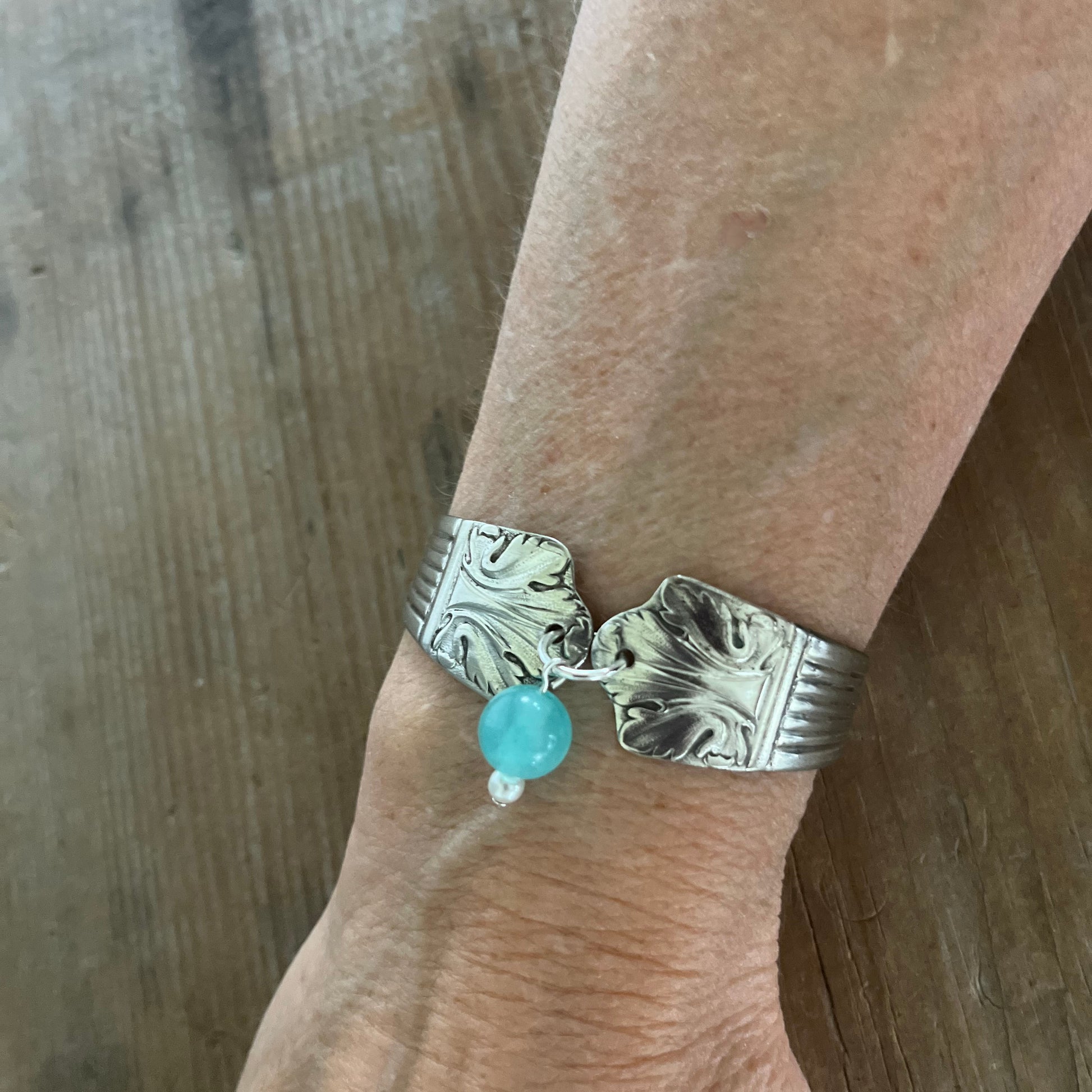 Lady Esther spoon link bracelet worn on wrist showing Art Deco design and teal glass bead charm with pearl drop - handcrafted from upcycled vintage silverware - Laughing Frog Studio