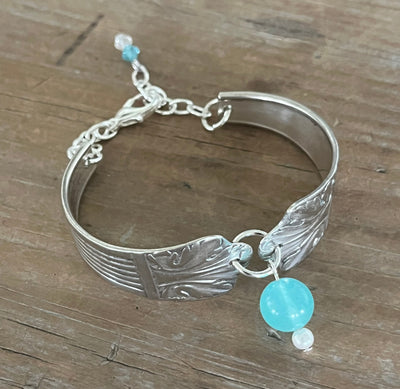 Top view of Lady Esther spoon link bracelet showing art deco design, teal glass bead charm, pearl drop, and adjustable silver chain - handcrafted from upcycled vintage silverware - Laughing Frog Studio