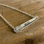 Close-up of hand-stamped VOTE silverware bar necklace pendant showing bold lettering and ornate floral graphic design on vintage silverplate handle - handcrafted from upcycled vintage silverware - Laughing Frog Studio