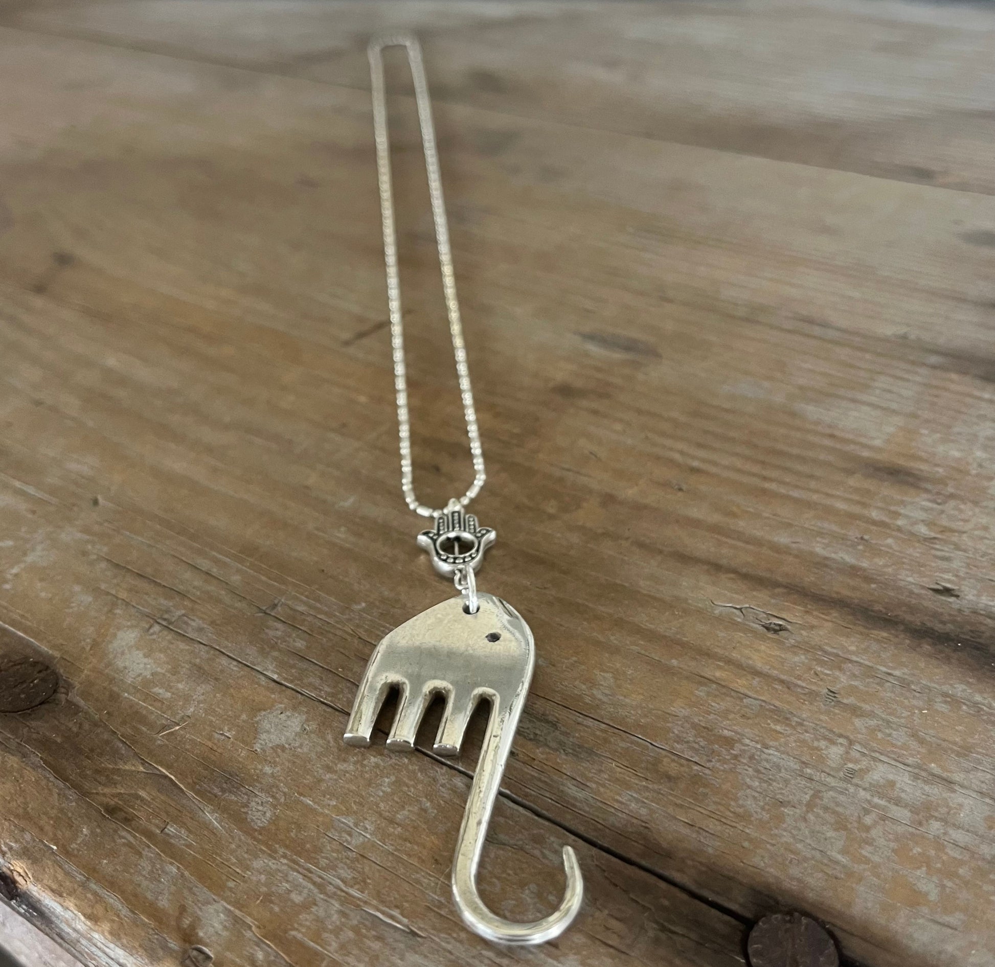 Fork elephant necklace with Hamsa hand charm on wood background - upcycled silverplate pendant necklace - handcrafted from upcycled vintage silverware - Laughing Frog Studio