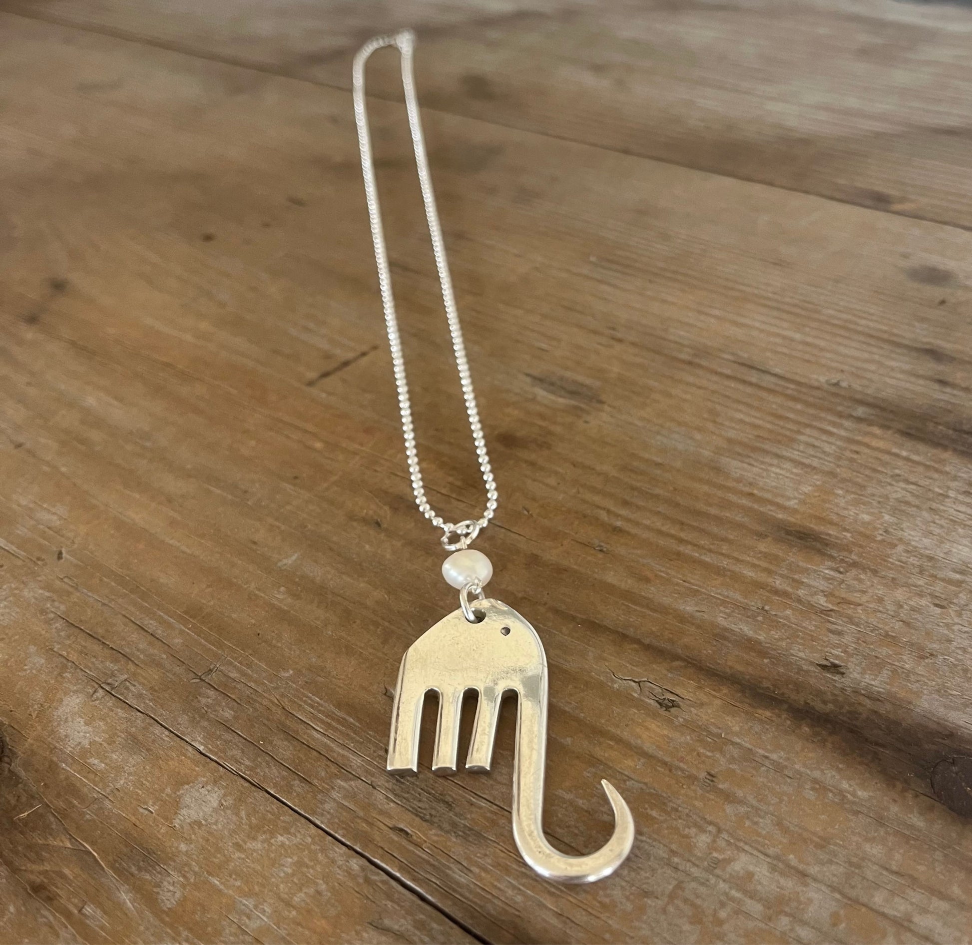 Fork elephant necklace with cultured pearl bead on wood background showing full chain length - handcrafted from upcycled vintage silverware - Laughing Frog Studio