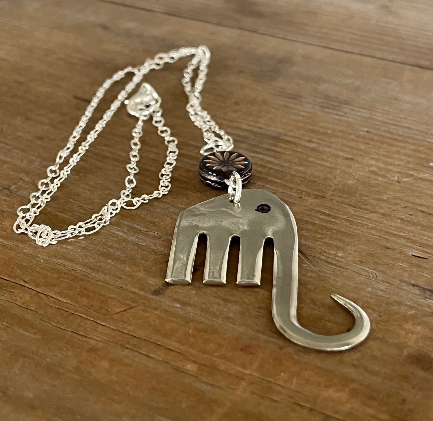 Close-up of fork elephant necklace with purple floral glass bead showing pendant detail - handcrafted from upcycled vintage silverware - Laughing Frog Studio