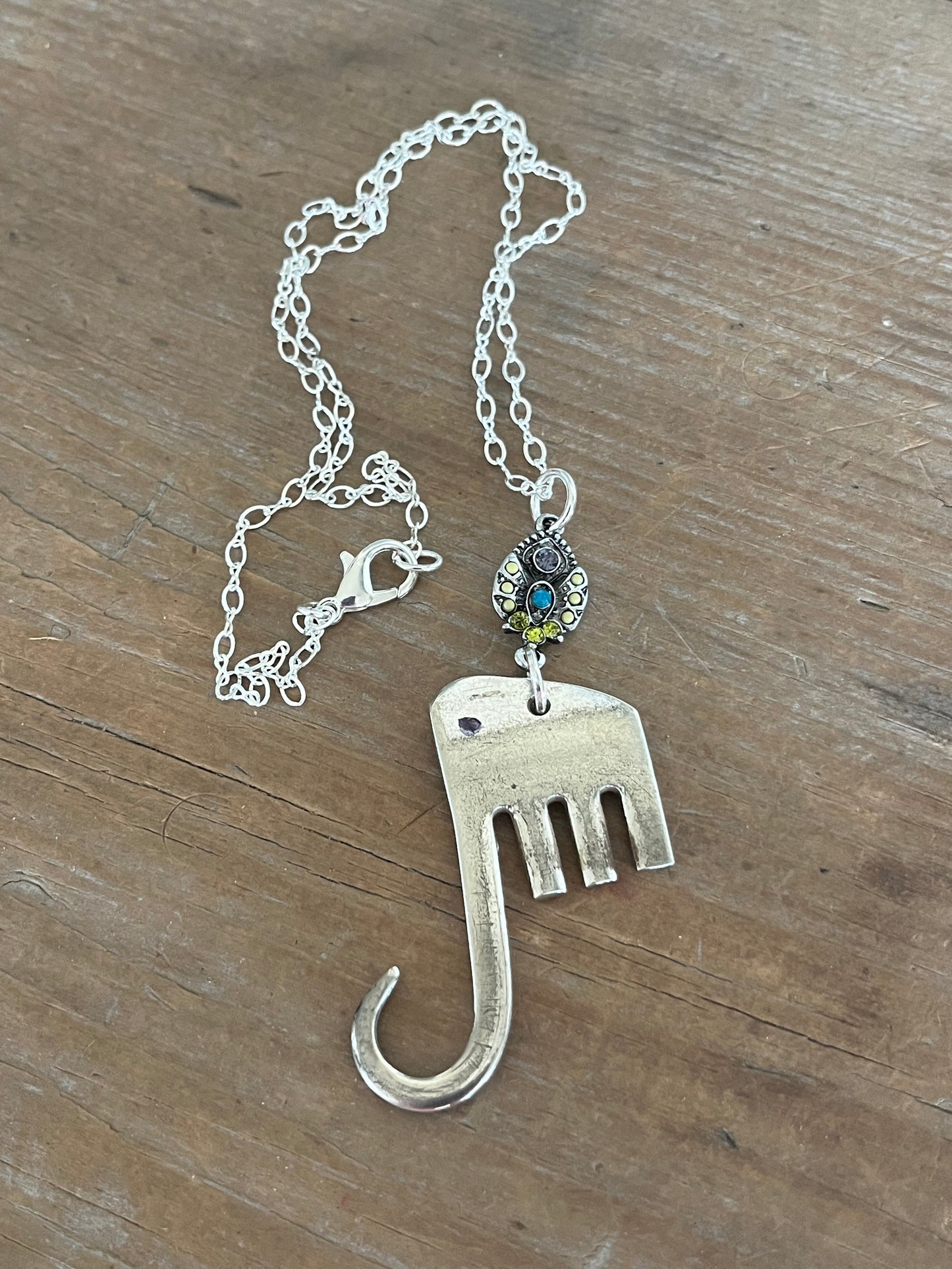 Fork elephant necklace with multicolor rhinestone bead on wood background showing full chain - handcrafted from upcycled vintage silverware - Laughing Frog Studio