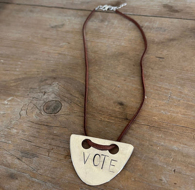 VOTE hand-stamped vintage spoon necklace on weathered wood showing full pendant and faux suede cord with metal links and clasp - upcycled silverware spoon necklace - handcrafted from upcycled vintage silverware - Laughing Frog Studio