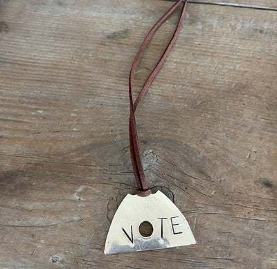 Close up of VOTE hand-stamped vintage spoon necklace on weathered wood - upcycled silverware spoon necklace - handcrafted from upcycled vintage silverware - Laughing Frog Studio