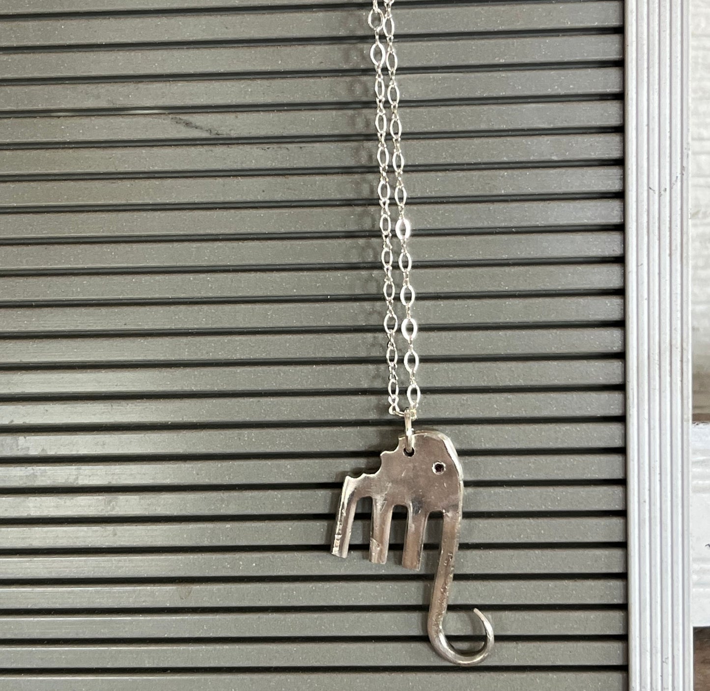 Fork elephant pendant hanging on silverplate chain against gray background - handcrafted from upcycled vintage silverware - Laughing Frog Studio