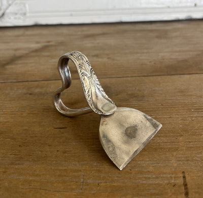 Ergonomic heart handle spoon cheese knife in Avalon pattern - angled view showing ornate silverplate detail and blade - handcrafted from upcycled vintage silverware - Laughing Frog Studio