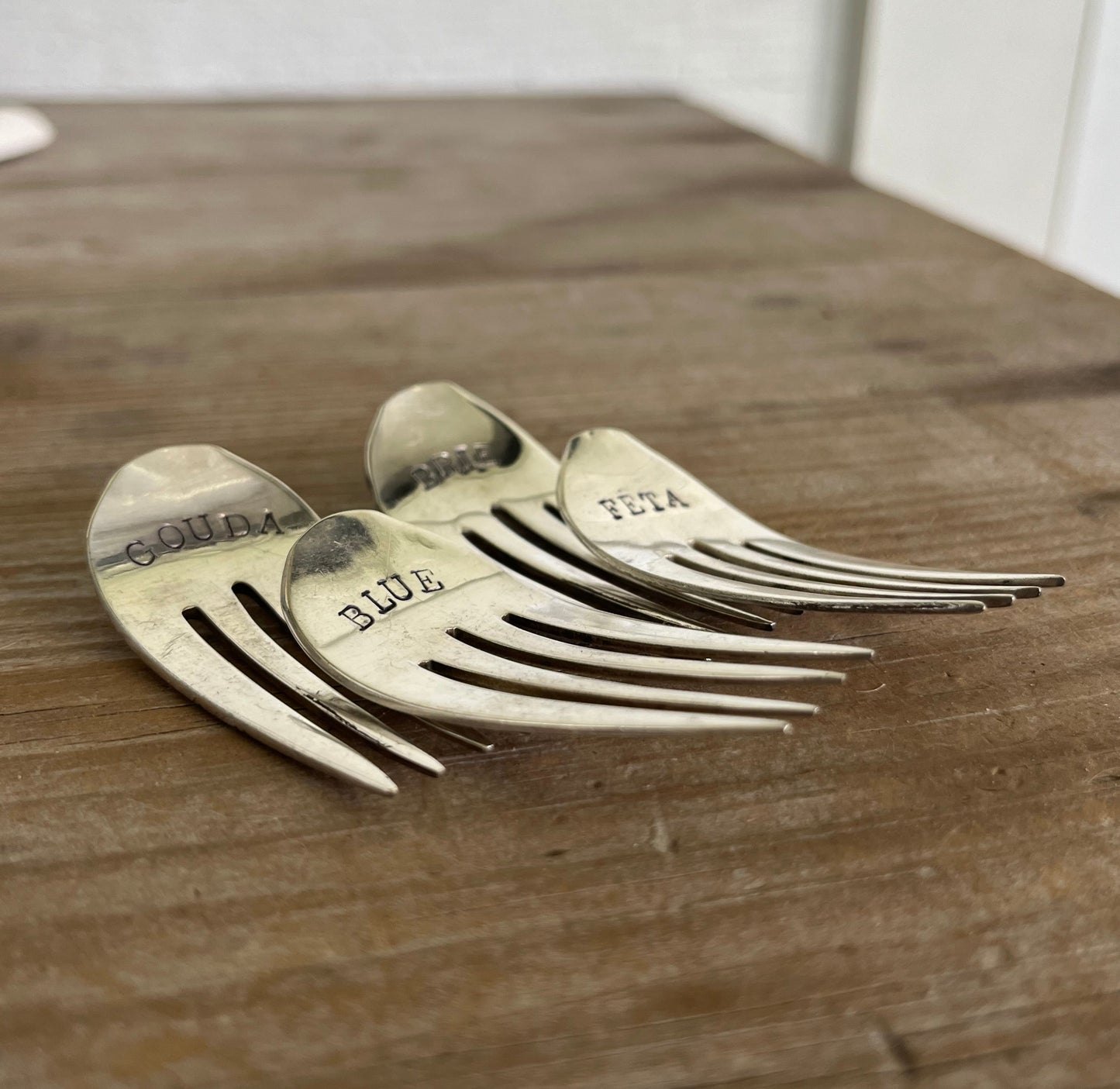 Hand-stamped vintage fork cheese markers detail - convex curved antique silverware with bold uppercase font