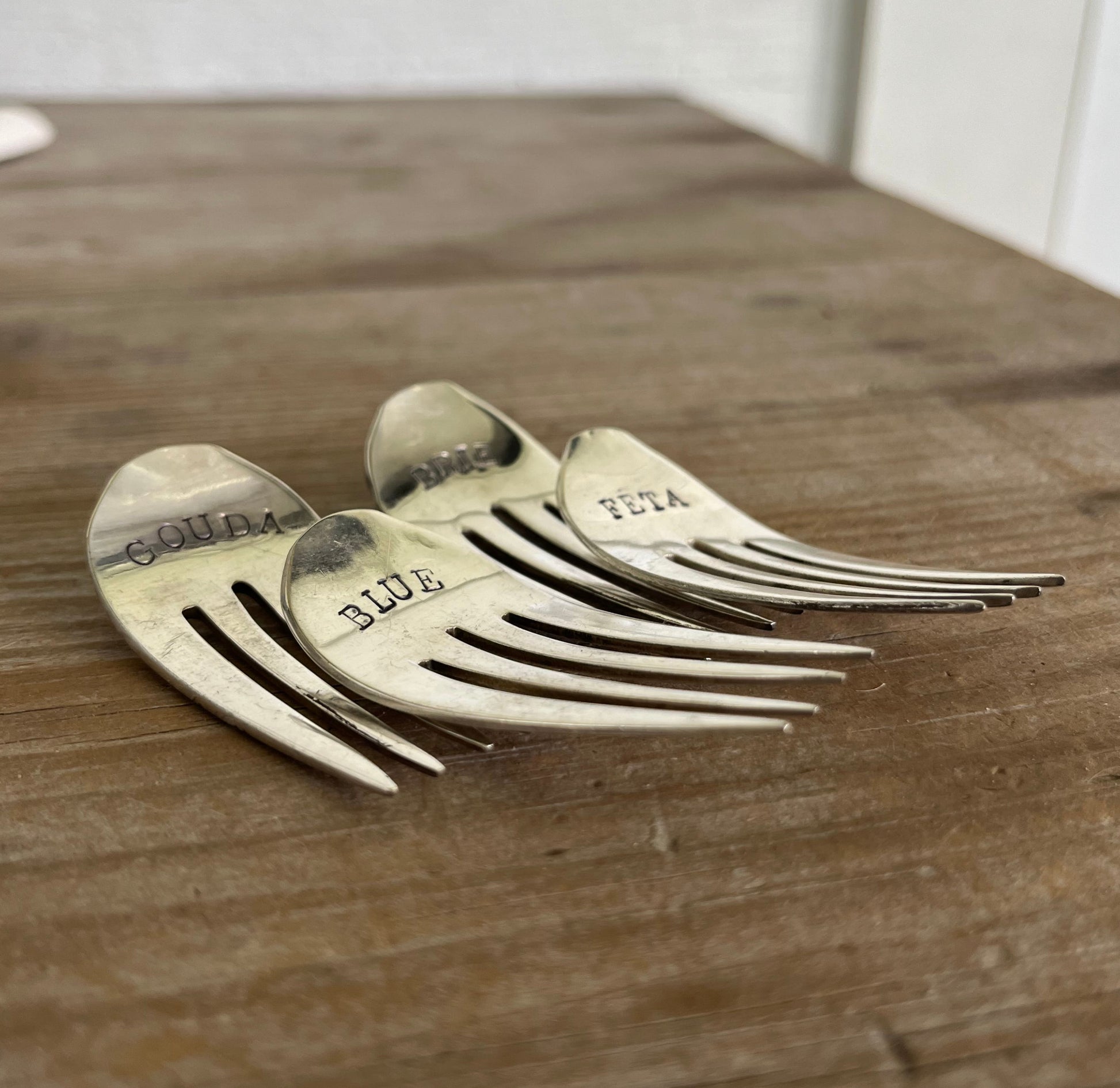 Hand-stamped vintage fork cheese markers detail - convex curved antique silverware with bold uppercase font
