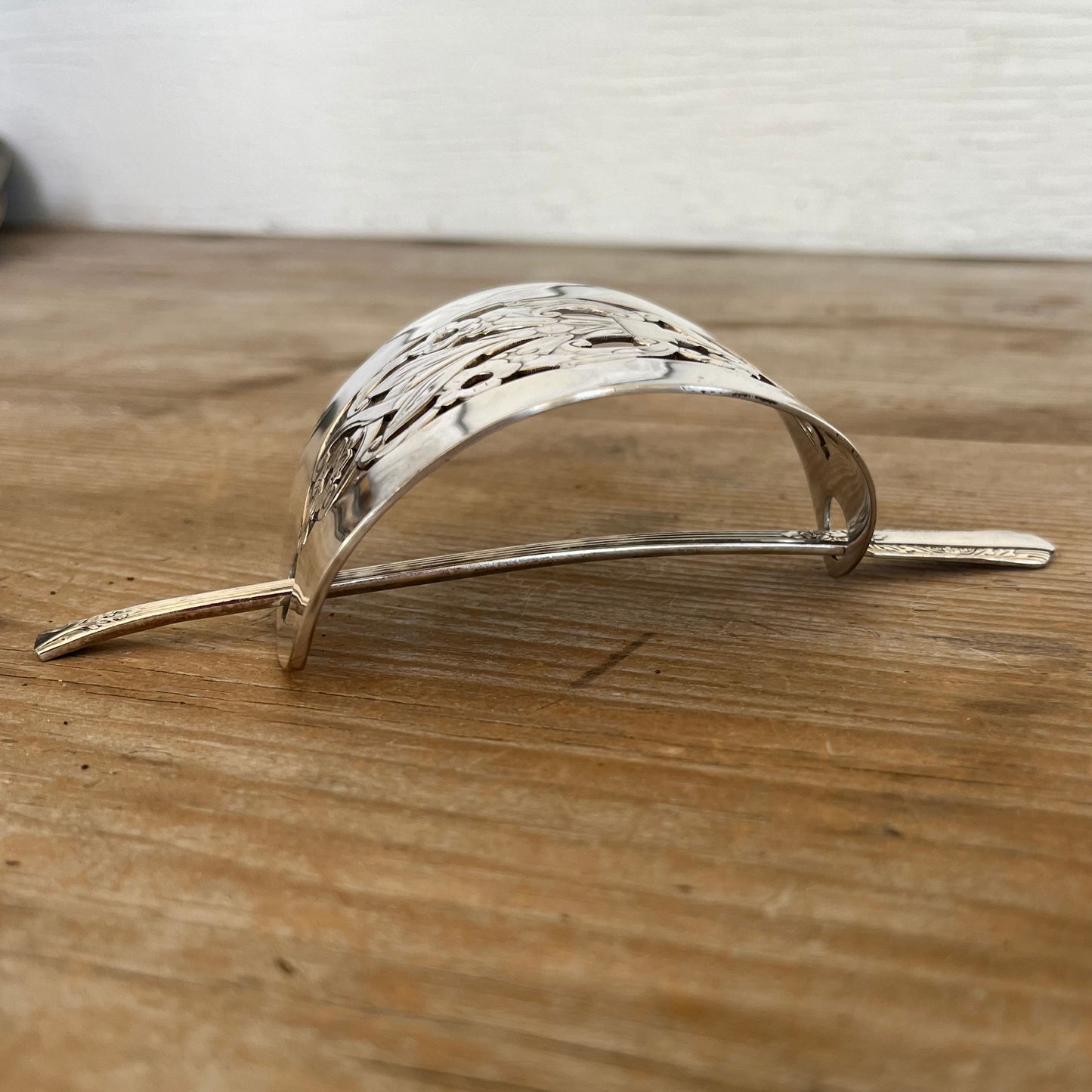 Side view of Art Deco cake server hair barrette showing curved vintage silverplate half-moon shape