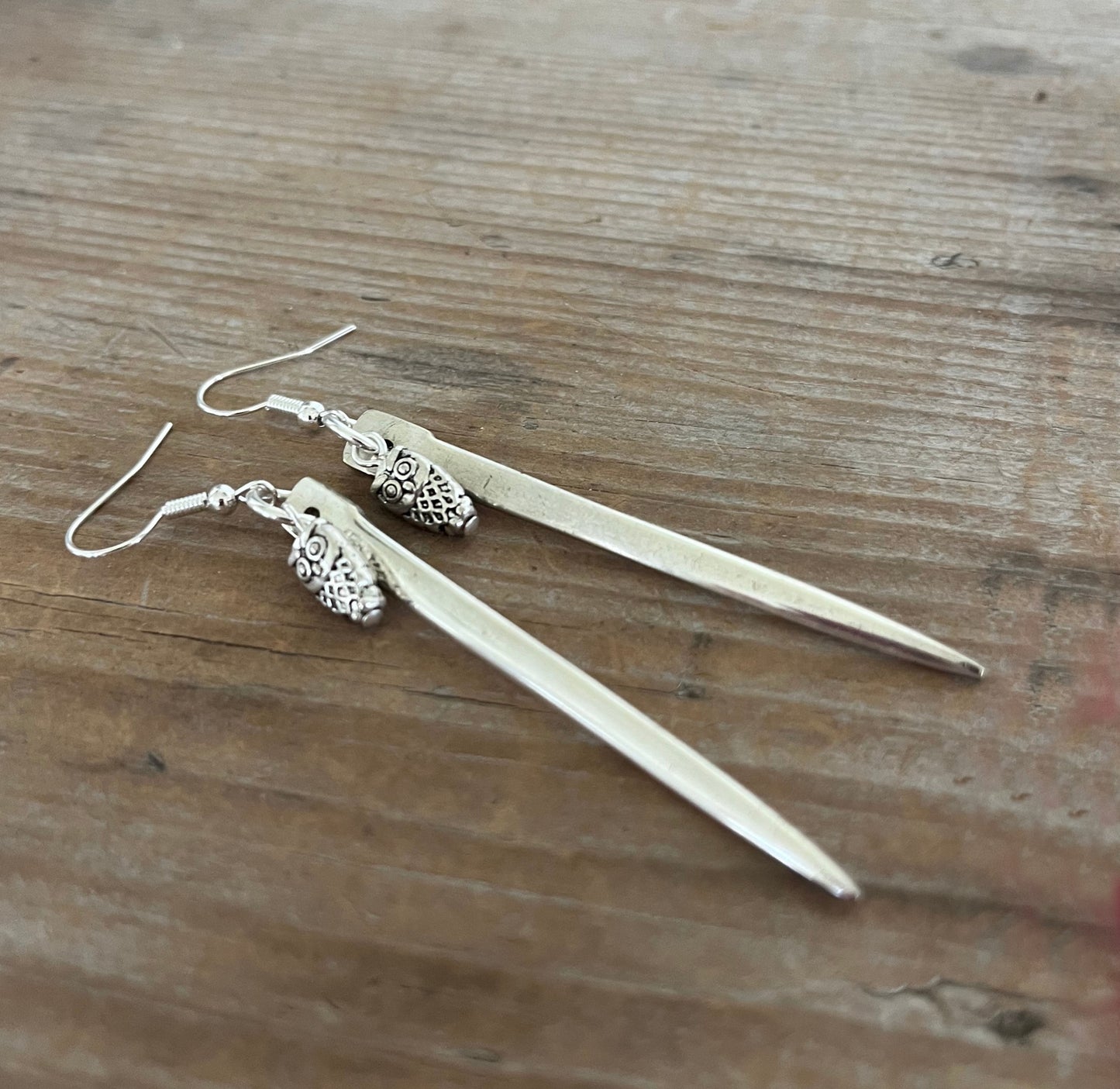 Close-up detail of edgy fork tine earrings with owl charms showing sharp clean lines, 3.25 inches long
