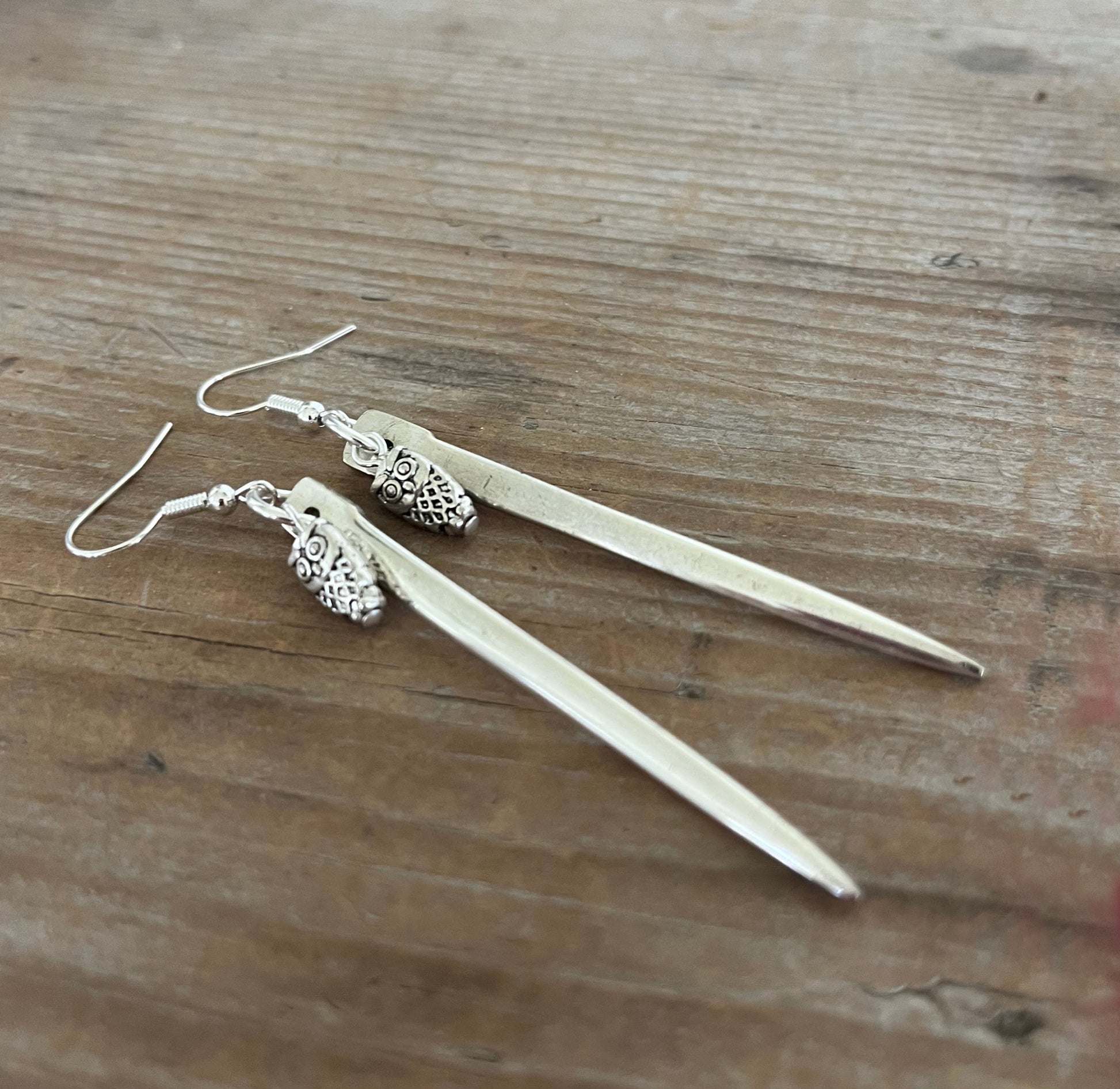 Close-up detail of edgy fork tine earrings with owl charms showing sharp clean lines, 3.25 inches long