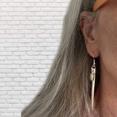 Fork tine earrings with owl charms modeled on ear displaying wearable fit and rebel energy style