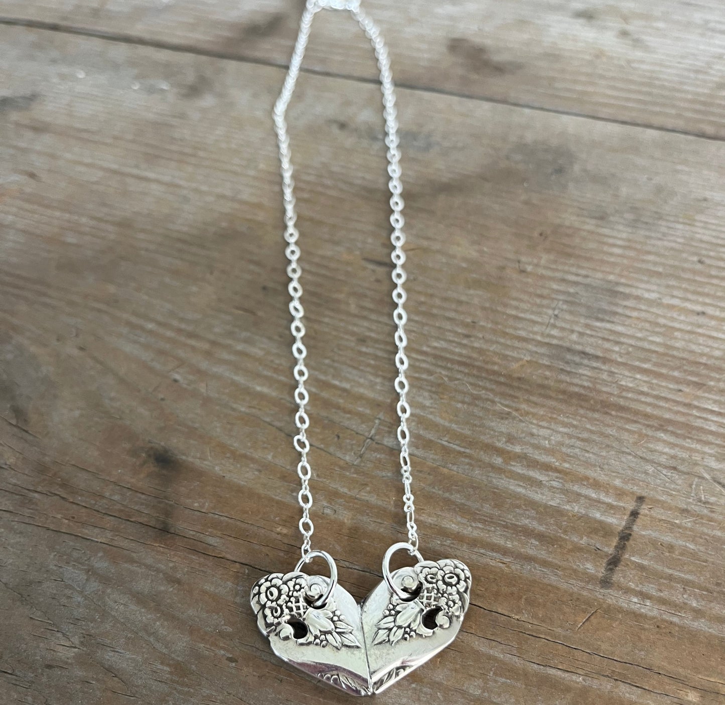 Close-up of Lovely Lady heart pendant showing intricate floral openwork pattern detail on vintage silverplate necklace