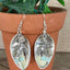 Close-up detail of spoon bowl earrings with hanging bird charm and faceted jadeite bead, 2.375 inches long - Spoon Earrings - handcrafted from upcycled vintage silverware - Laughing Frog Studio