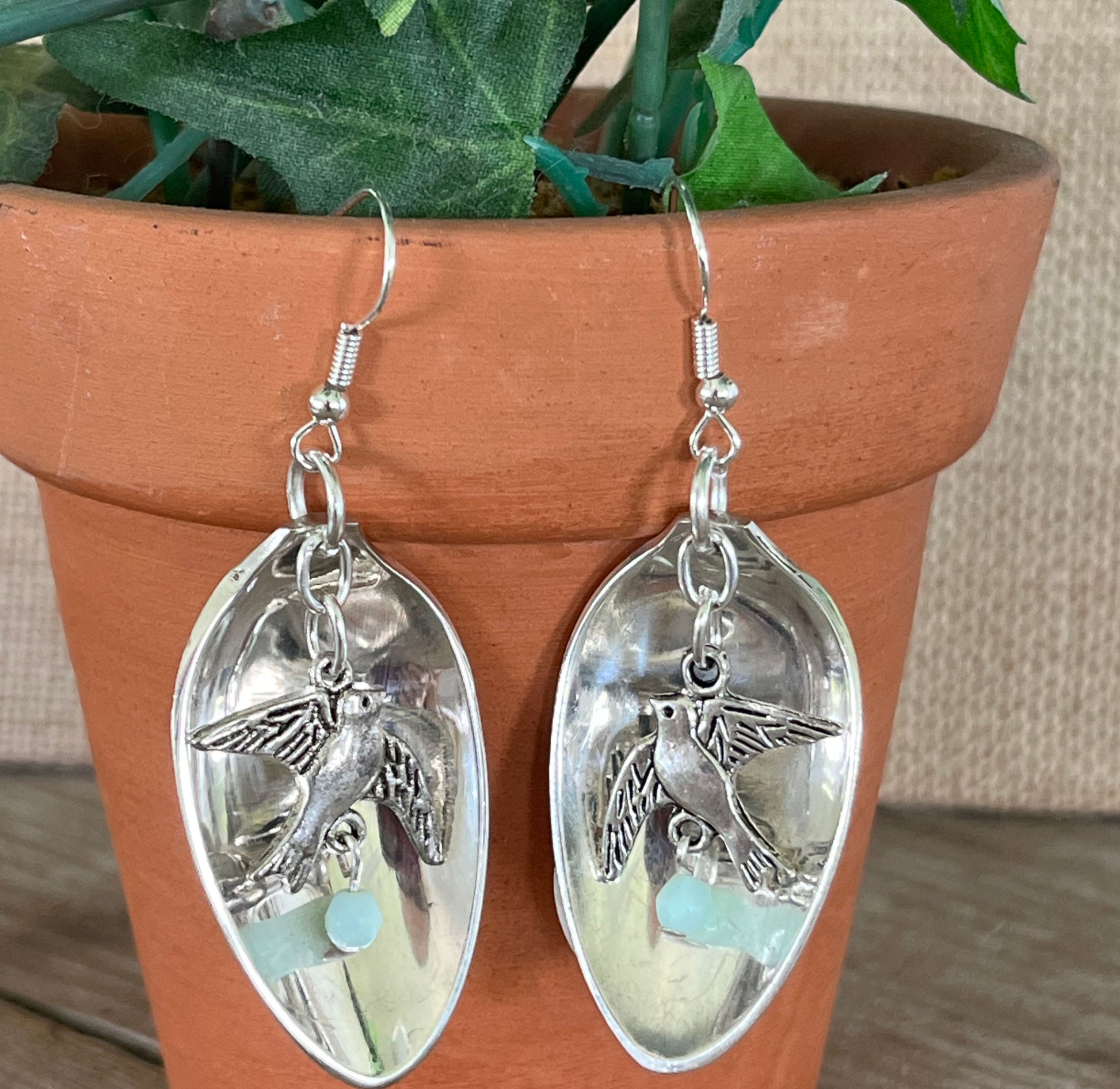 Close-up detail of spoon bowl earrings with hanging bird charm and faceted jadeite bead, 2.375 inches long - Spoon Earrings - handcrafted from upcycled vintage silverware - Laughing Frog Studio