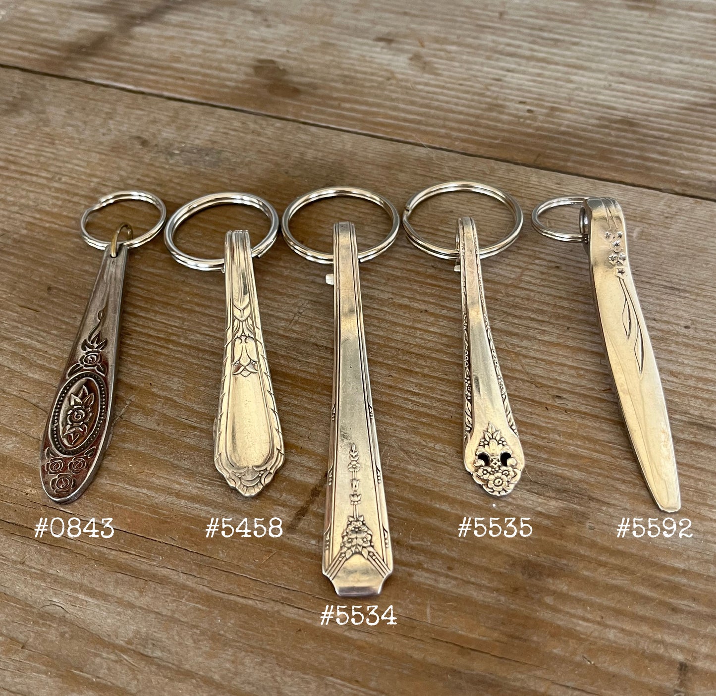 Detailed view of vintage spoon handle keychains showing upcycled silverware patterns and ornate details