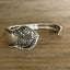 Detailed photo of William Rogers & Son Orange Blossom pattern spoon cuff bracelet with ornate floral repousse pattern on weathered wood - handcrafted upcycled vintage silverware cuff - Laughing Frog Studio