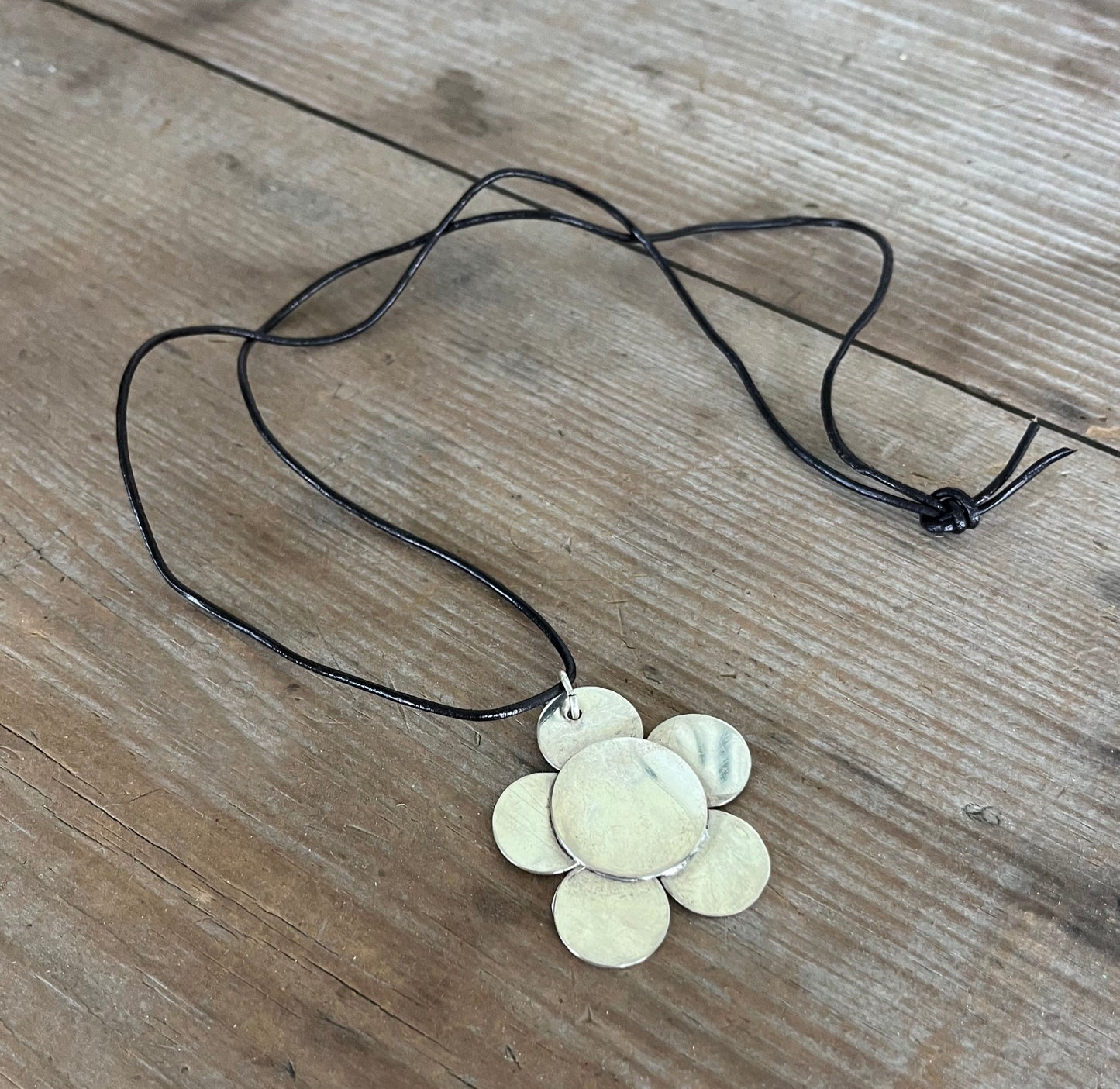 Artisan spoon bowl pendant necklace with punch-out daisy design hanging on a leather cord — handcrafted from upcycled vintage silverware — Laughing Frog Studio