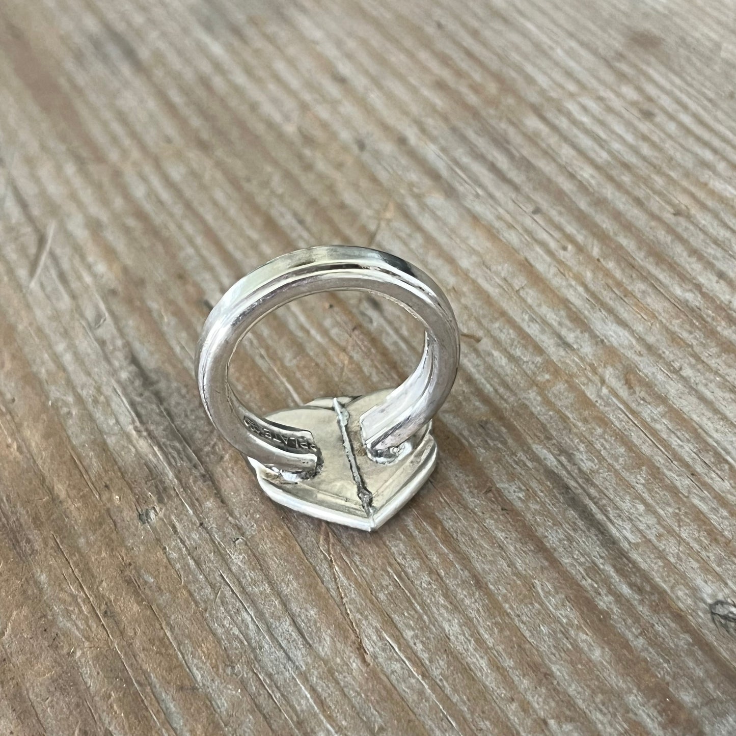 Detail of handcrafted spoon heart ring showing antique silverplate patina and artisan metalwork