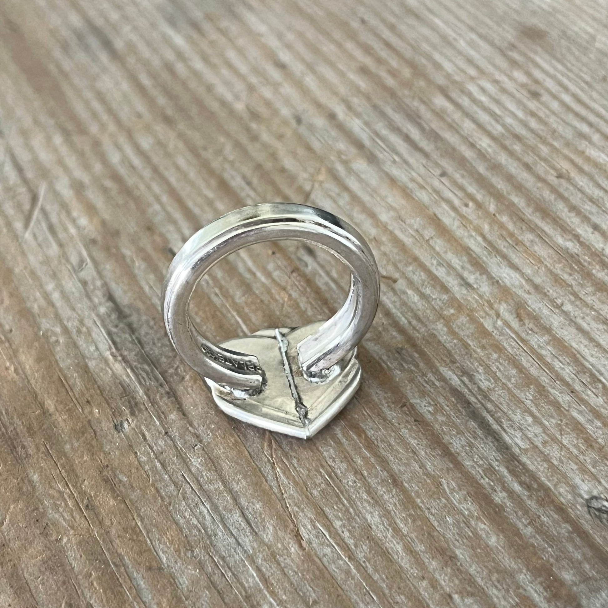 Detail of handcrafted spoon heart ring showing antique silverplate patina and artisan metalwork