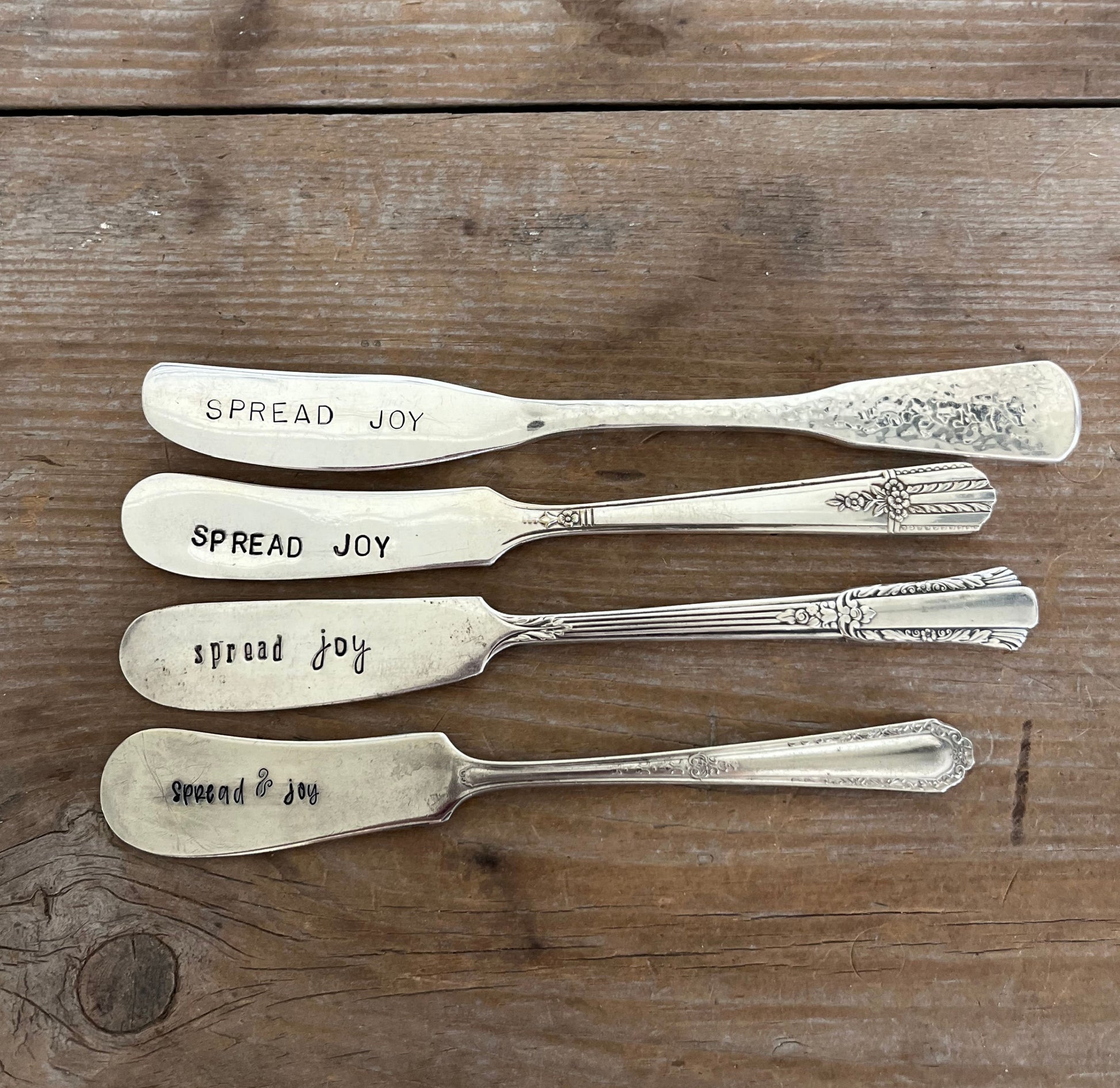 Collection of vintage butter knives transformed into Spread Joy cheese spreaders with hand-stamped lettering