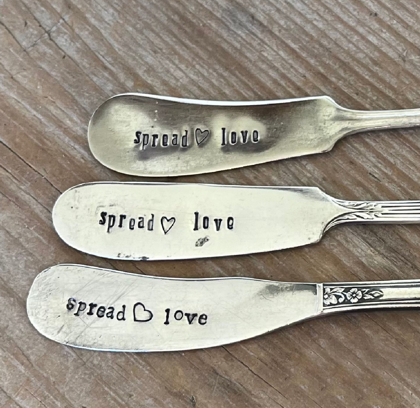 Close-up of SPREAD LOVE message hand-stamped on vintage silverware cheese spreaders