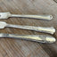 Close-up of handles on SPREAD LOVE hand-stamped vintage knives cheese spreaders one-of-a-kind upcycled silverware gift